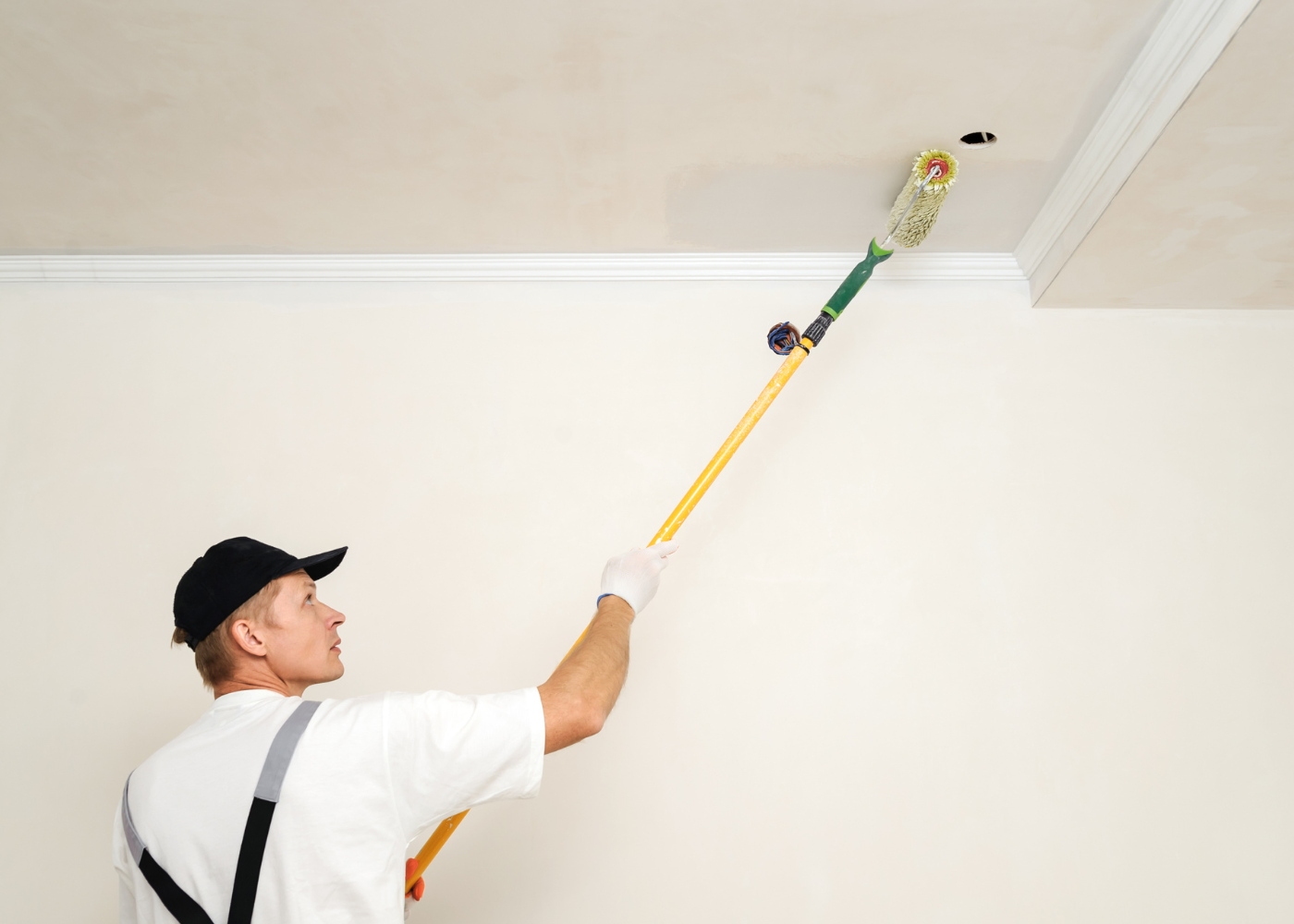 Professional painter painting a ceiling with long brush. 