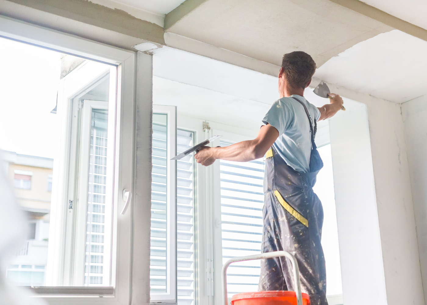 individual standing on ladder working on ceiling before painting