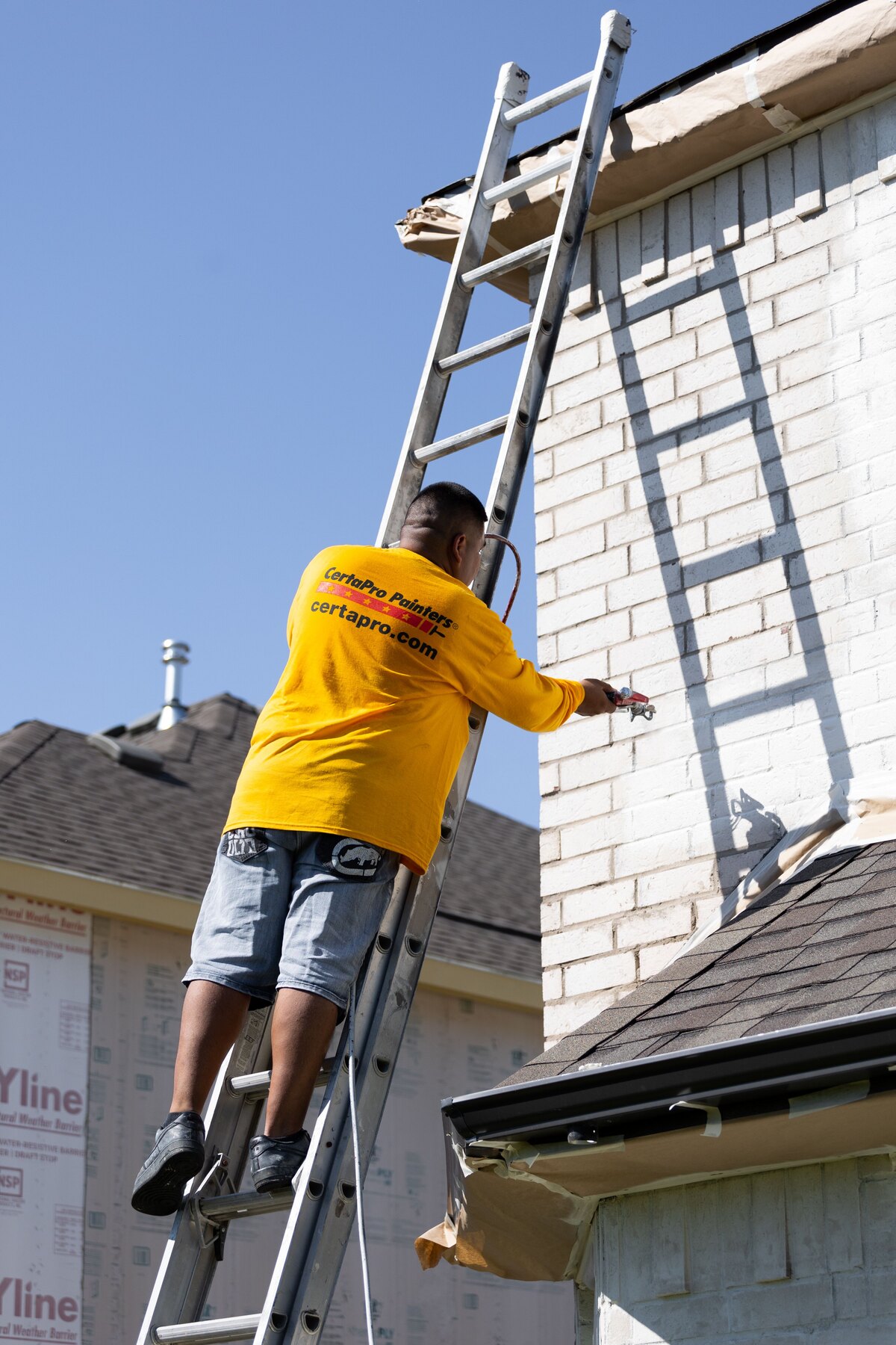 CertaPro painter working on an exterior under clear weather conditions