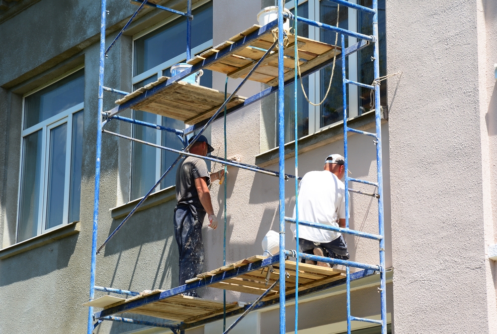 men on scaffolding painting stucco