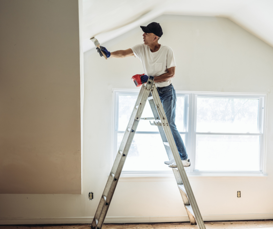 man on ladder painting the interior of an apartment