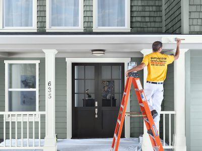 painter on ladder painting exterior trim
