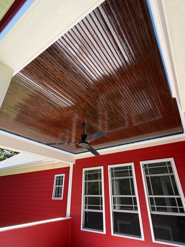 stained porch ceiling against red sided house