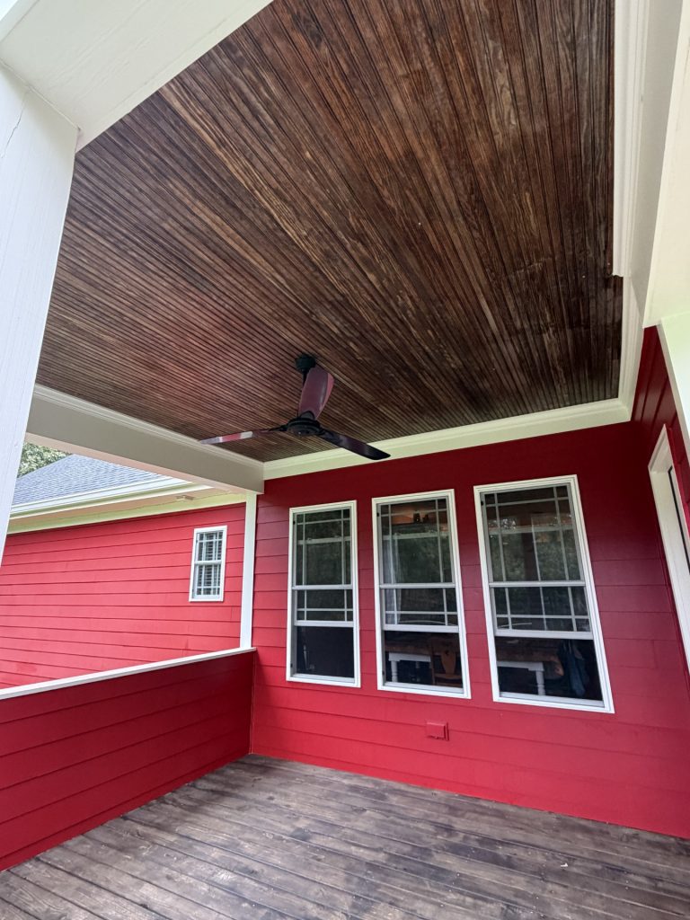 wooden porch ceiling against house with red siding