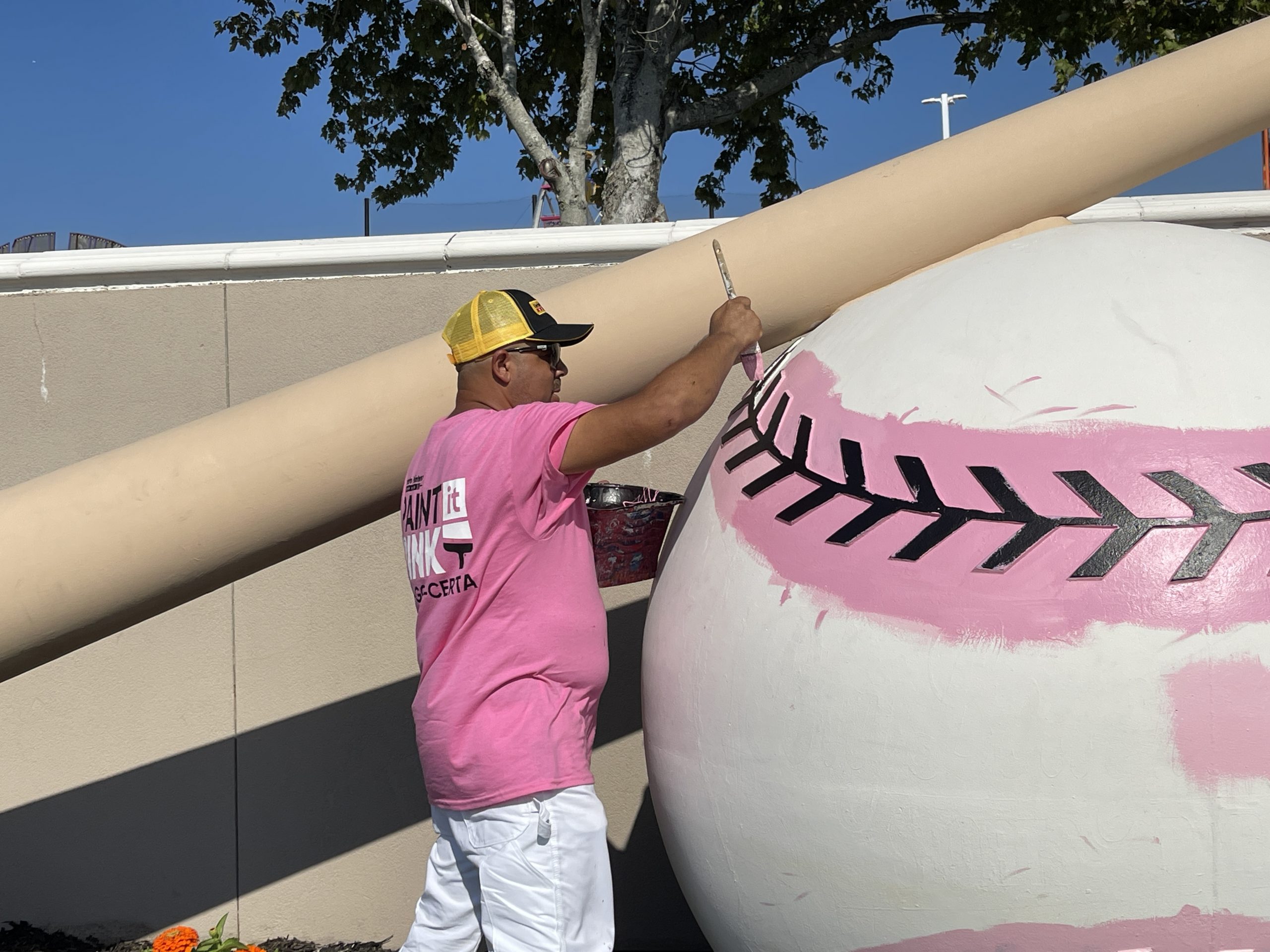 man painting baseball sculpture pink