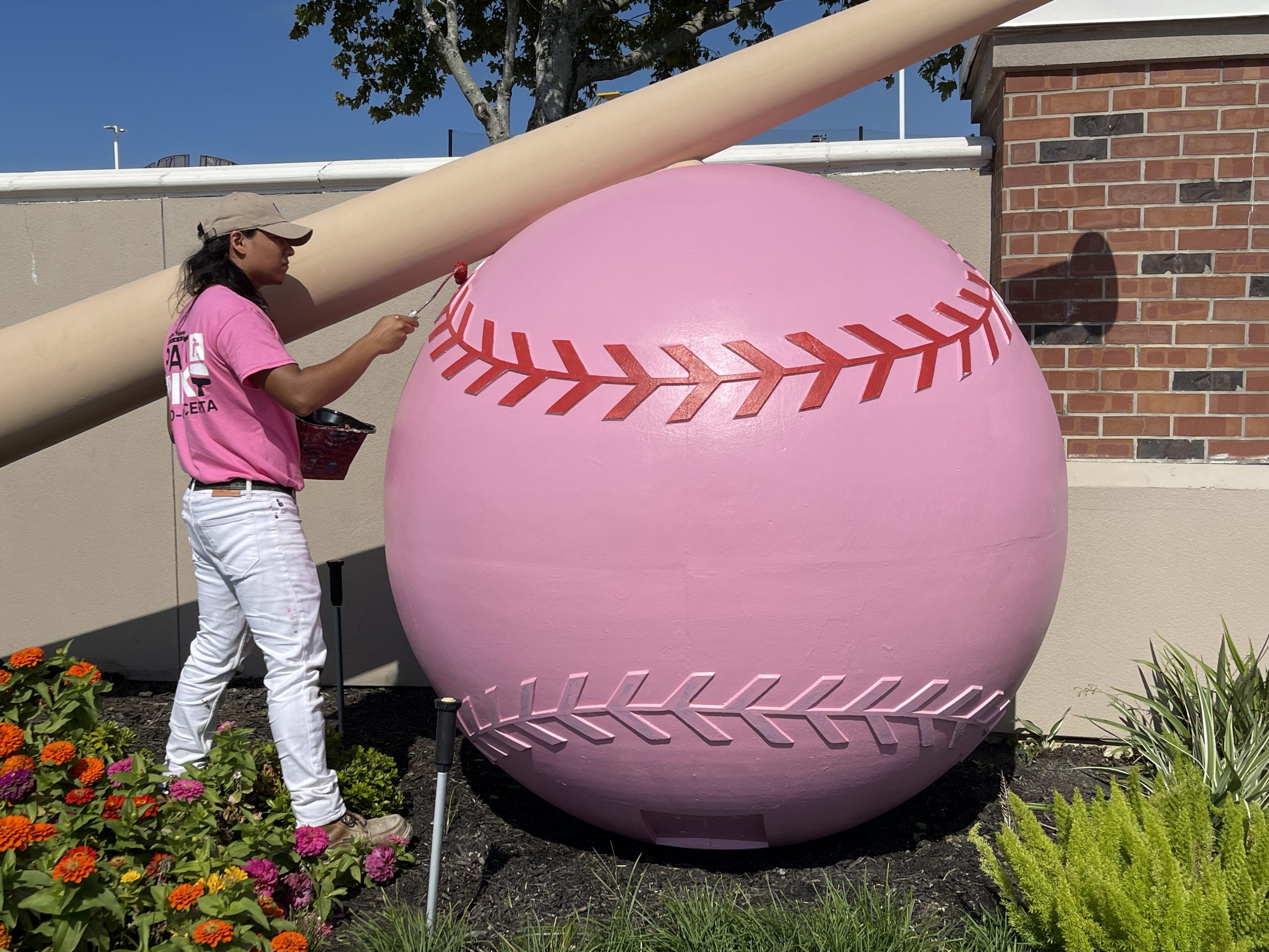 man painting baseball sculpture pink