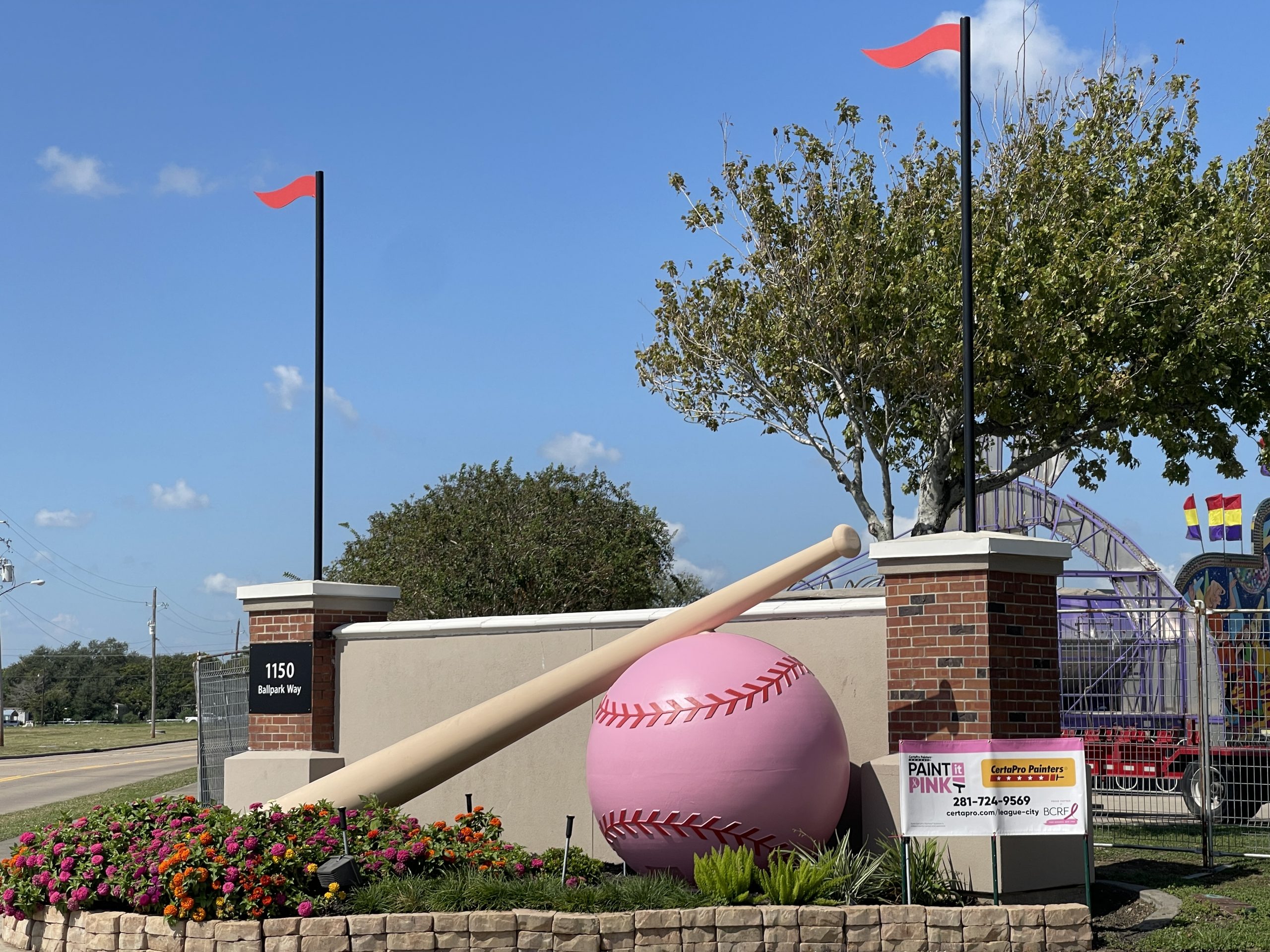 pink painted baseball and bat sculpture at ballpark entrance