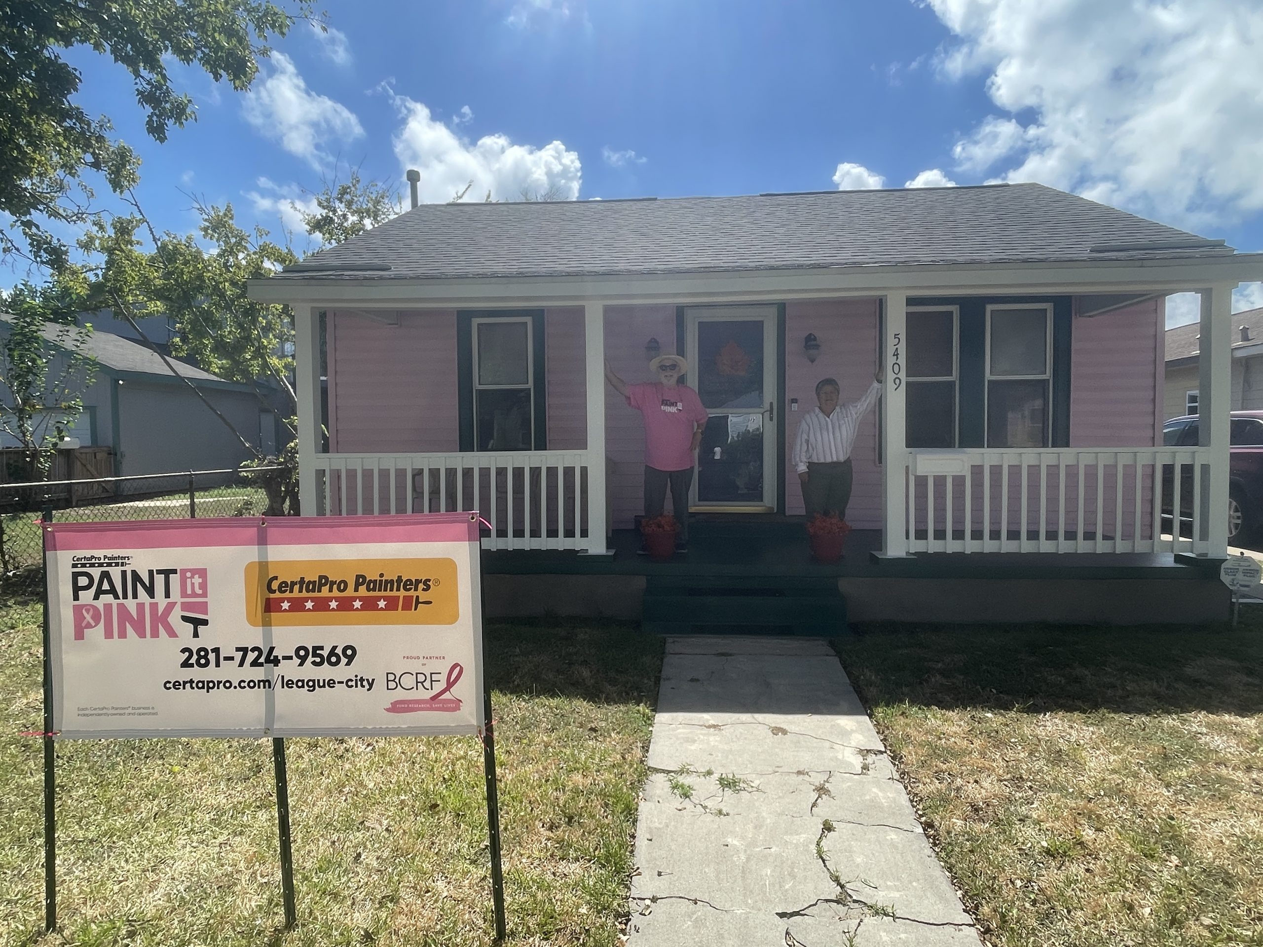 two people on porch of pink painted house