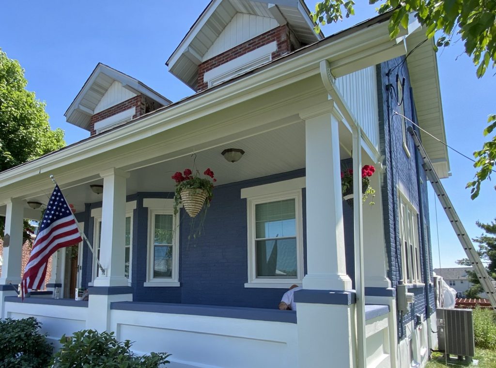 blue painted brick house with white trim and white front porch
