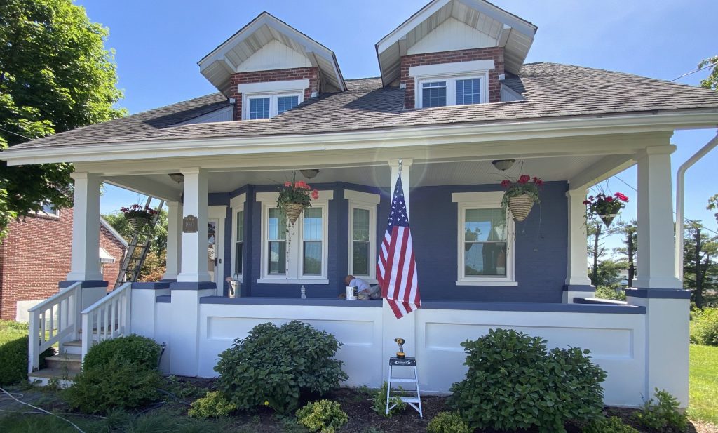 front of blue painted brick house with white trim and white front porch