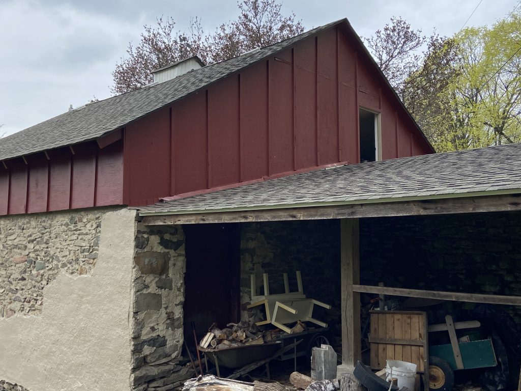 dark maroon paint on top half of barn, bottom half concrete and stone