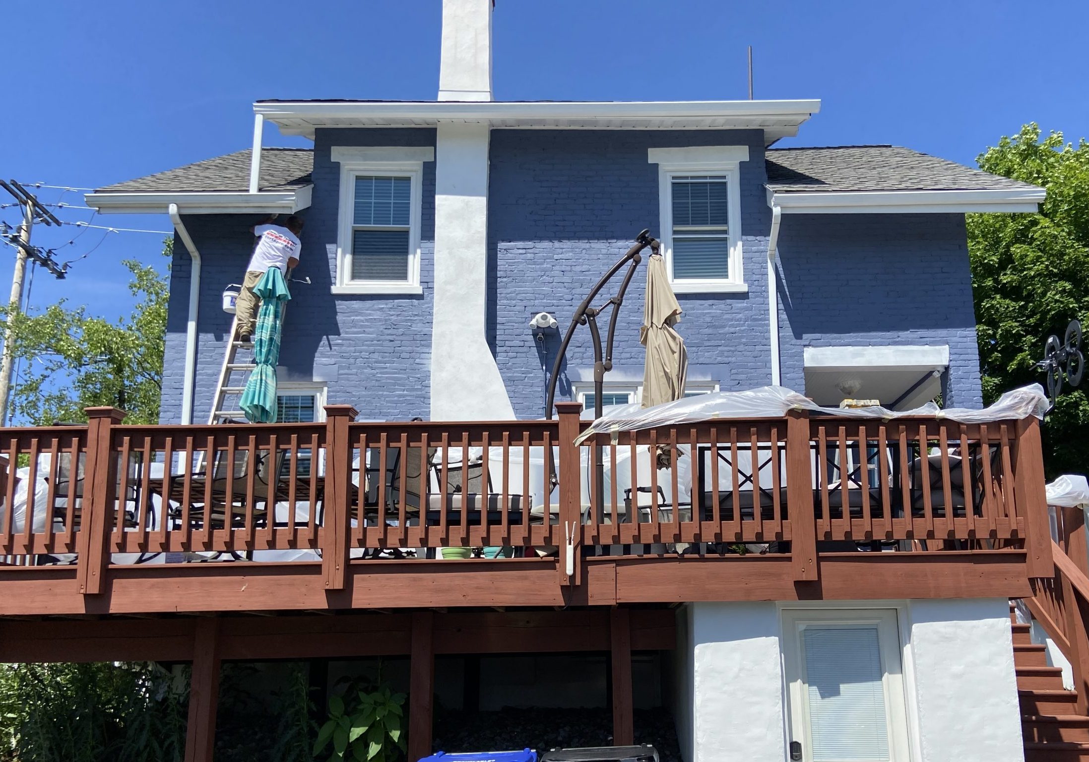 Blue painted brick house with white chimney and brown deck