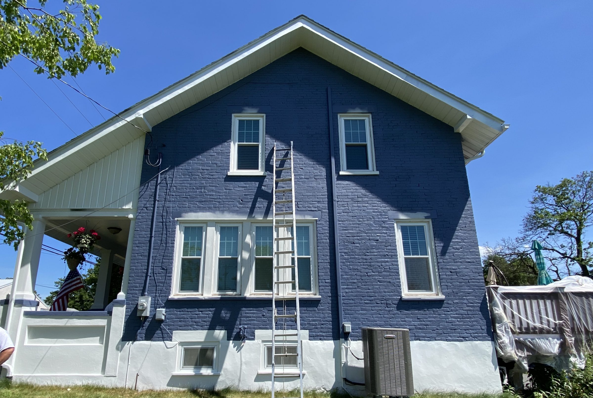 side of brick house painted blue with white trim and porch