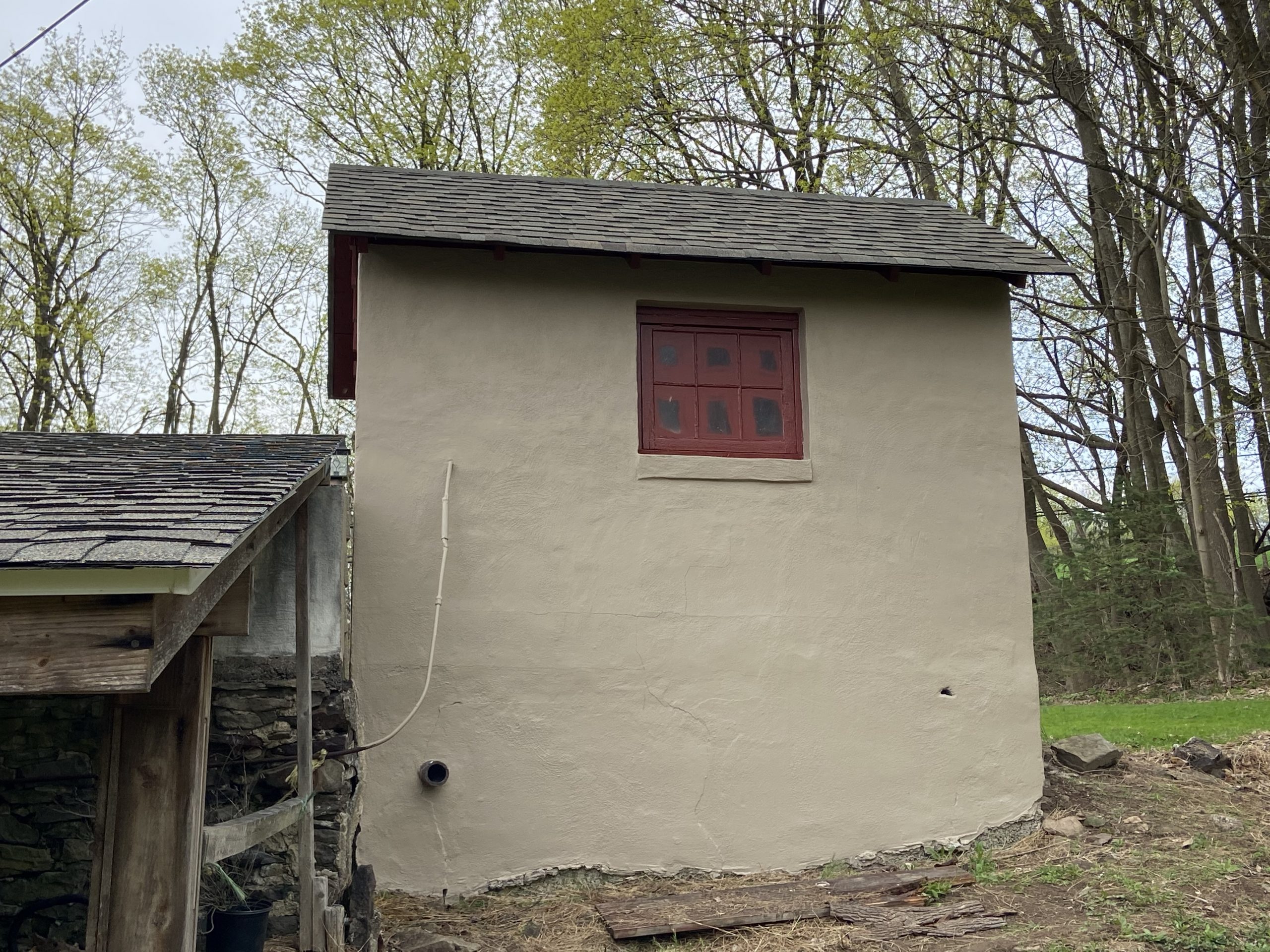 side tan pained shed with small maroon window
