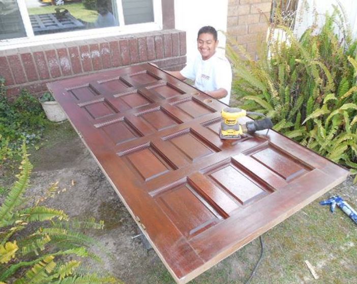 man working on staining a front door.