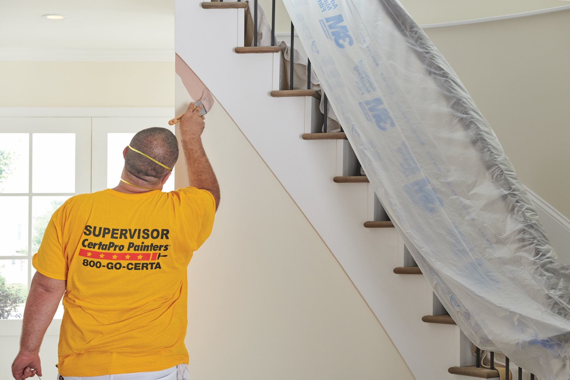 painter painting interior wall with mask on