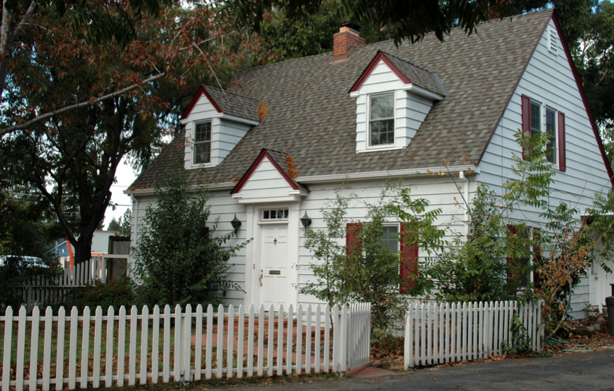 White cape cod style home with reddish shutters