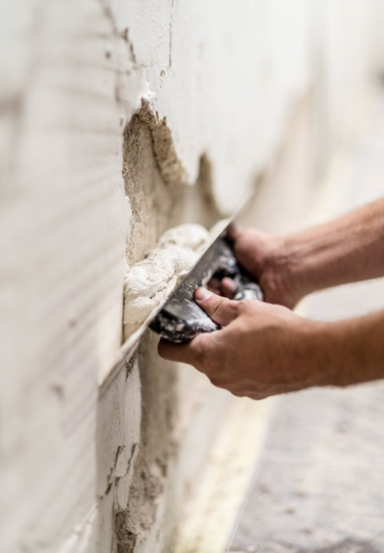 Hands holding trowel to repair plaster wall