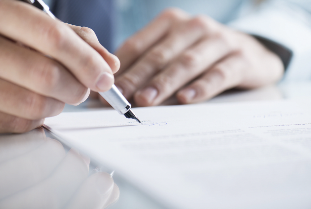 Hands holding a fountain pen writing something on white paper