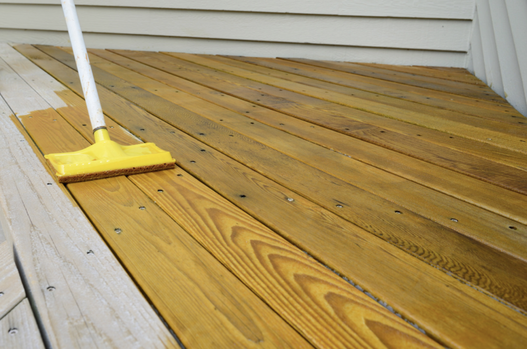 New deck with a tinted transparent stain being applied and wood grain showing through the stained wood