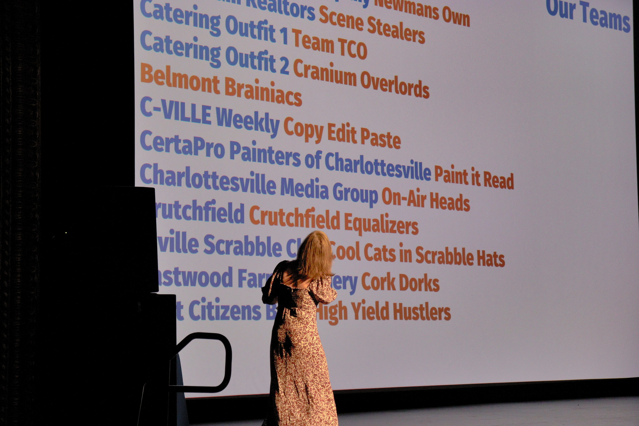 woman standing in front of large projection of team name list