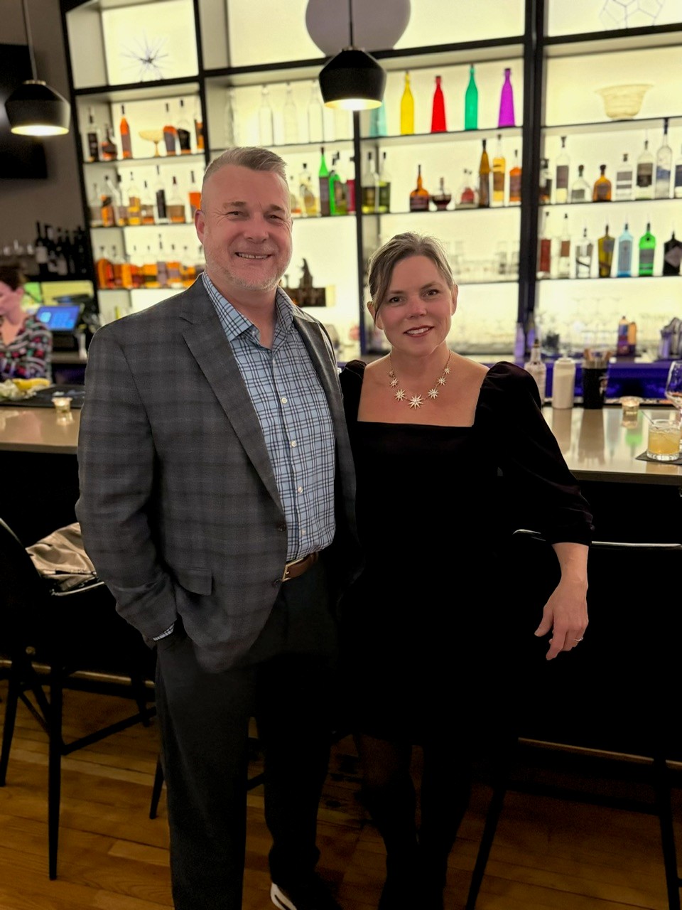 couple standing in front of bar