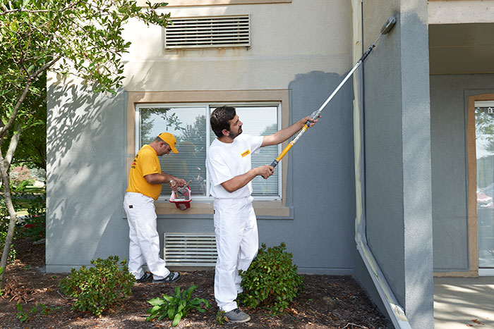 two certapro team members exterior painting stucoo home