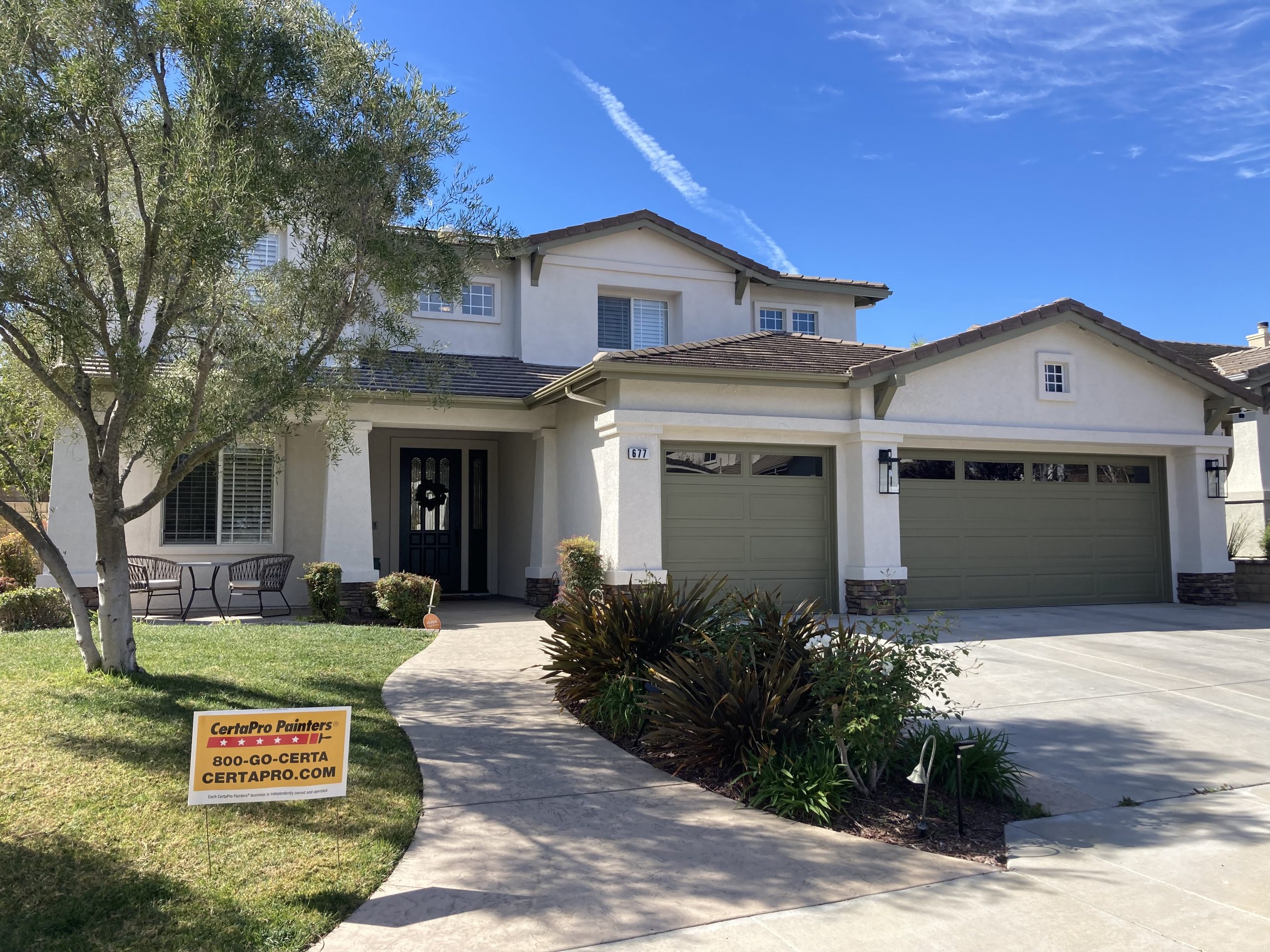 white painted stucco exterior with green garage doors