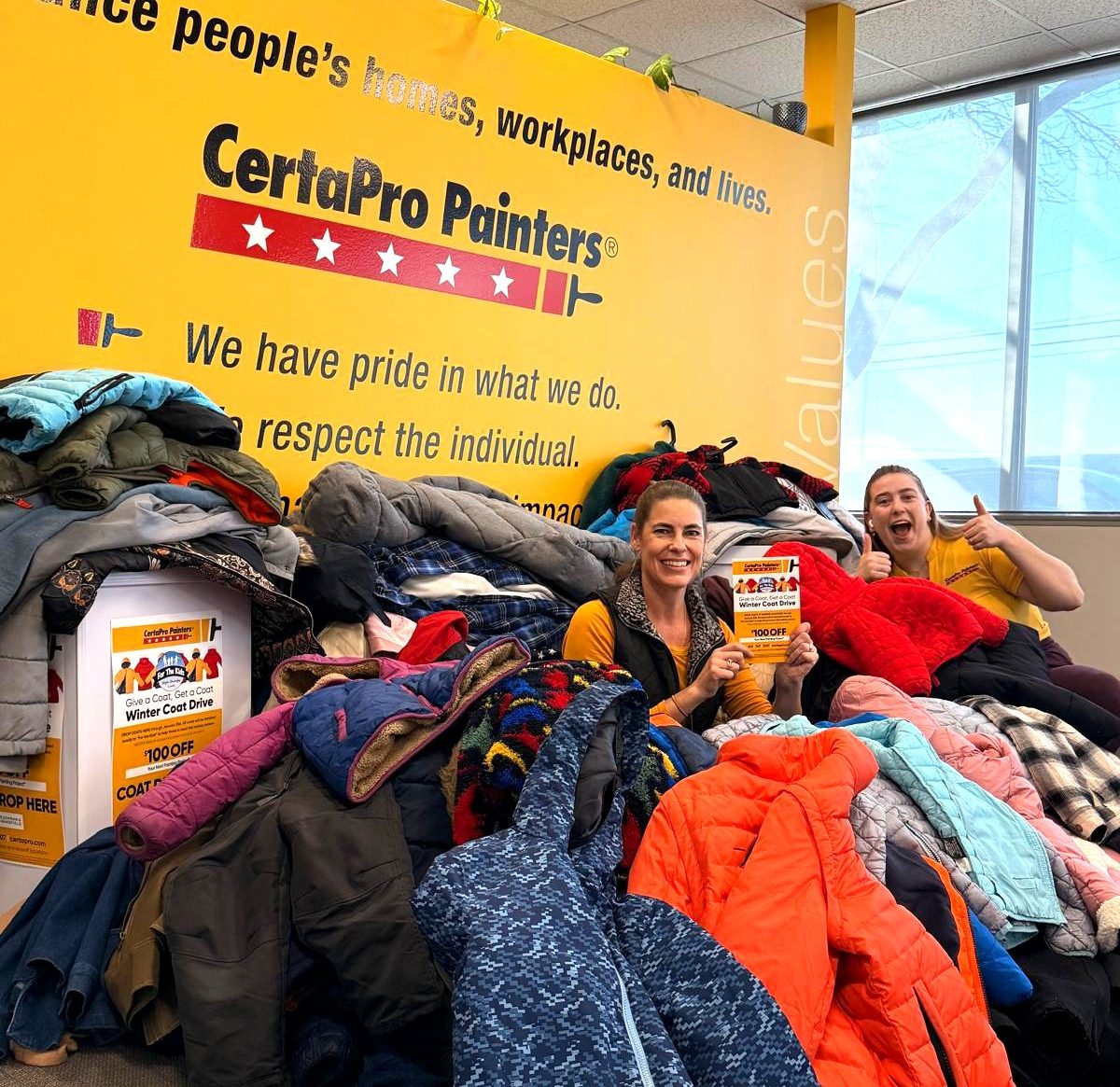 two people sitting in donated coat pile