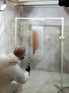 CertaPro Team Member painting a kitchen cabinet door with a paint sprayer