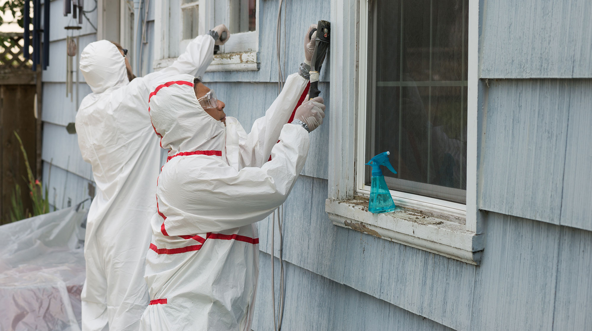 Painters preparing the exterior of a house in East San Diego before repainting it.