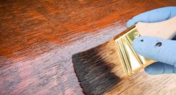 brush applying wood stain to wood surface