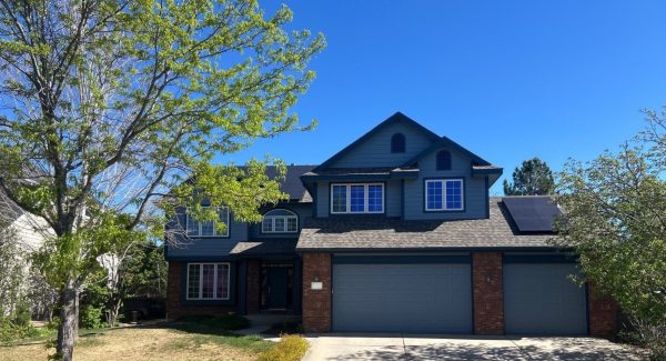 front exterior of brick house with blue painted siding and garage