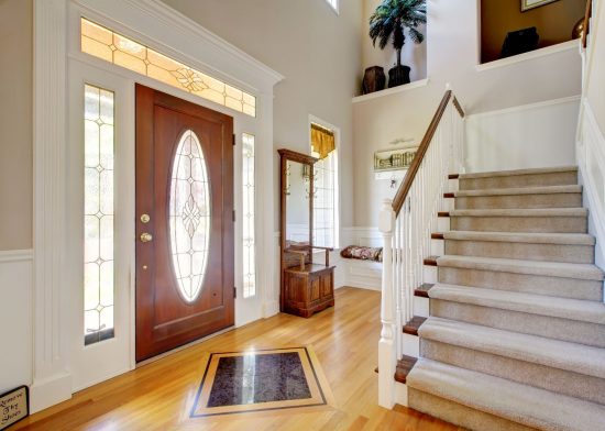 Modern foyers with staircase. Door and banister are stained while walls and trim are white.