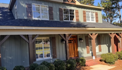house with green painted siding and rust colored accents and posts