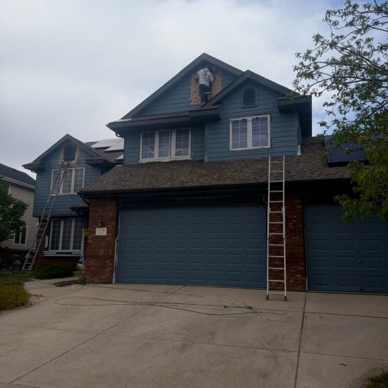 front exterior of brick house with blue painted siding and garage