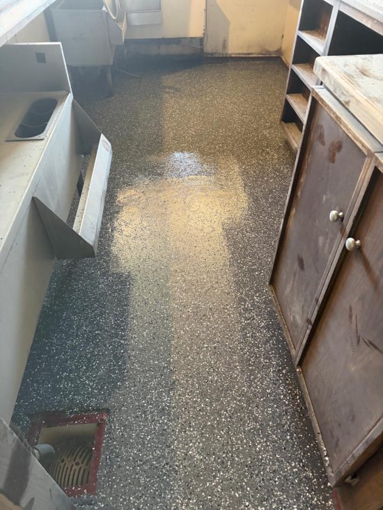 Grey flake epoxy floor under wooden bar cabinets at Echo Brewing after commercial flooring installation.