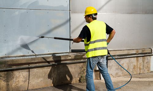 CertaPro employee pressure washing side of building