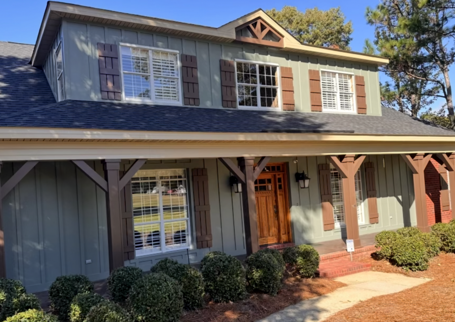 house with green painted siding and rust colored accents and posts